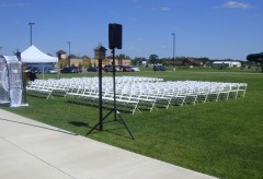 Outdoor wedding ceremony setup with lots of white chairs on the grass